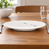 J812C-HM Rain Flower round plate with concentric ridges and low foot beside fork, knife, bowl and water glass
