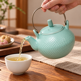 Celadon textured teapot pouring into a separate white cup