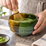 K537-GB green and amber bowl during matcha whisking; whisk is a styling prop