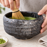K537-KK charcoal matcha bowl during active whisking; whisk is a styling prop