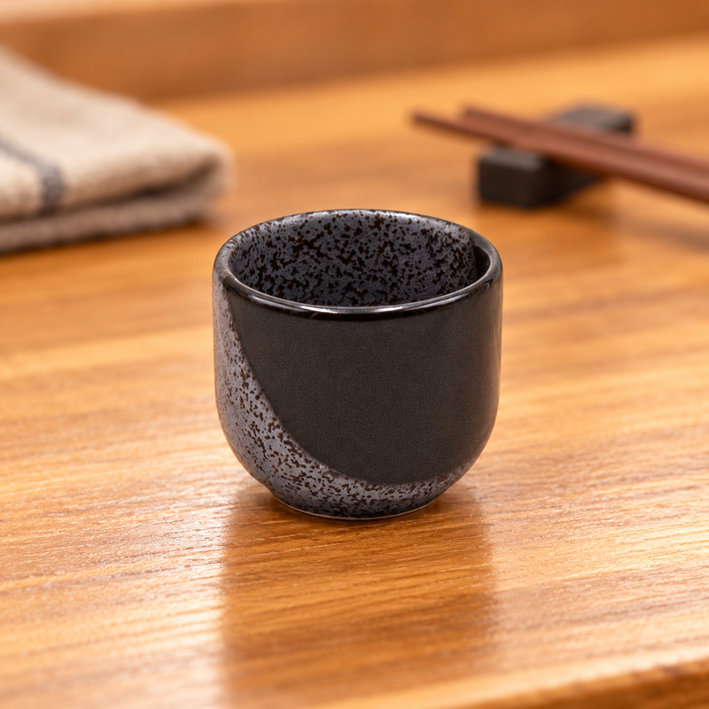 KY8-NW black and grey speckled ceramic sake cup on a wooden table