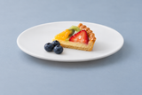 White round melamine plate with fruit tart and blueberries