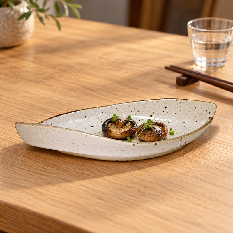 MA311-WK cream speckled leaf-shaped plate with two small grilled mushrooms in a restaurant setting