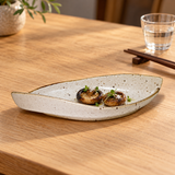 MA311-WK cream speckled leaf-shaped plate with two small grilled mushrooms in a restaurant setting