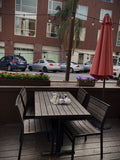 Mocha Stackable Indoor/Outdoor Chair with Black Aluminum Frame in a restaurant setting; other furniture is illustrative