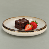 Ivory shallow ceramic plate with dark rim holding chocolate cake