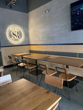 Natural solid ashwood seat and back restaurant chair with metal frame; restaurant setting with other furniture illustrative