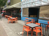 Orange open-back plastic restaurant chair; restaurant setting, other furniture illustrative
