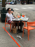 Orange open-back plastic restaurant chair; restaurant setting, other furniture illustrative