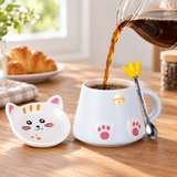 Coffee poured into pale-blue cat-paw mug with lid and spoon alongside