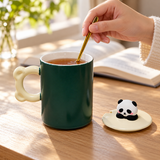 Dark green panda mug reverse in a stirring-use scene, matching lid beside it