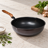 12.60" Aluminum Stir-Fry Pan with Wood Handle on a restaurant preparation counter