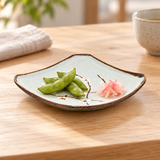 Square floral plate with edamame and pickled radish on a wooden table