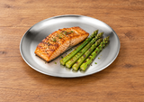 Round silver plate with salmon and asparagus on a wooden table