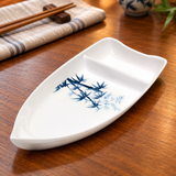 10-BZ white boat-shaped dish with blue bamboo pattern on a wooden restaurant table