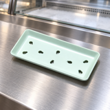 Light green 2110-G sushi-case plate on a stainless sushi preparation counter
