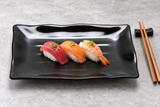 24120BK black rectangular plate presenting three pieces of nigiri sushi