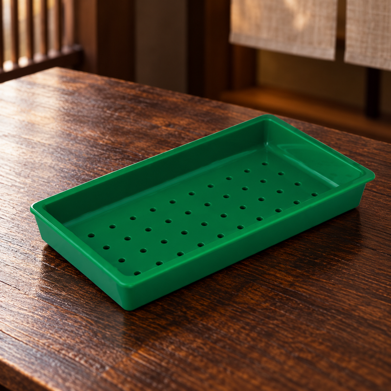 Green 91178 perforated melamine sushi case plate on a wood counter