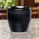 A1888-B black ceramic sake cup on a light stone dining counter