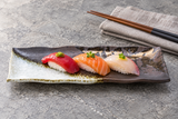 IM211-WK brown and white porcelain plate serving three nigiri in a stone-table dining setting