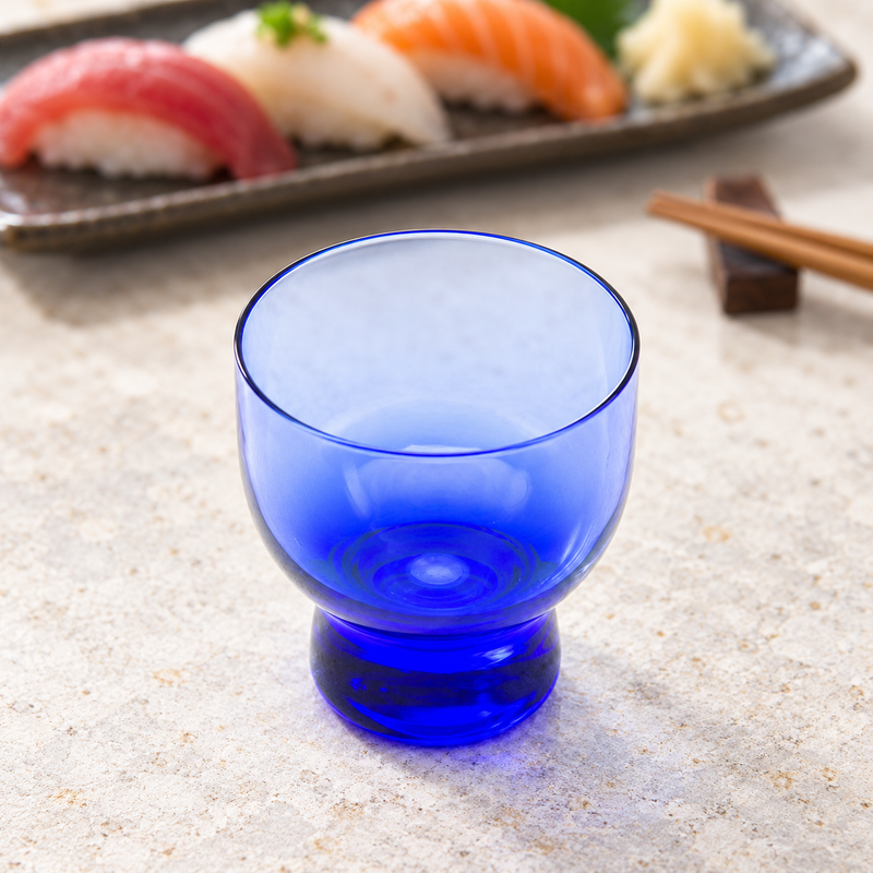 Blue transparent JN24-B glass sake cup at a stone tabletop setting