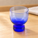 JN24-B blue glass sake cup on a wooden restaurant table