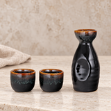 JX12-1 black and brown sake set with one bottle and two cups on a pale stone counter