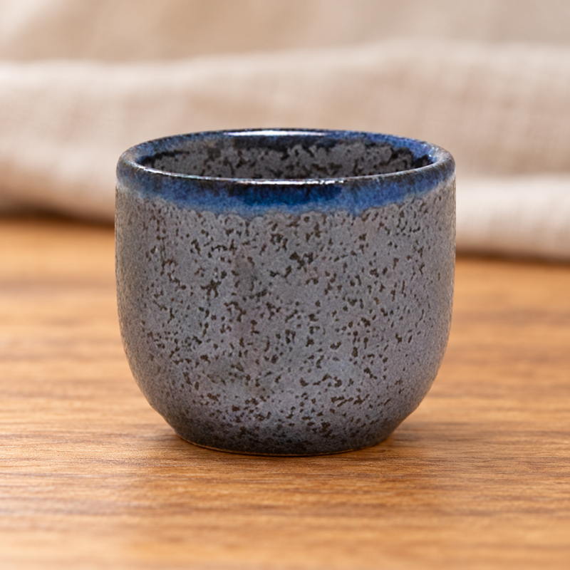 Stony-black KY8-BK porcelain sake cup with a blue rim on a wooden table