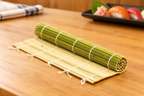 SM34-11 partially rolled green bamboo sushi mat on a wooden sushi bar work surface