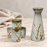 TSS83 gray blossom sake set with one bottle and four cups on a pale tabletop with linen
