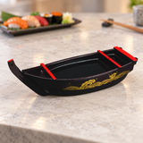 WM874 dark burgundy sushi boat with red trim and gold wave ornament displayed empty on a stone dining counter