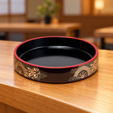 WO-17-4 black sushi oke with red rim and gold wheel pattern displayed empty on a wooden restaurant counter