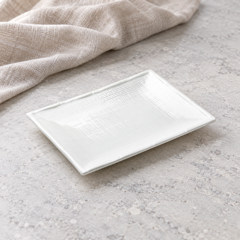 A0940 white textured plate on a stone table with its raised curved edges visible