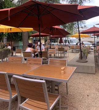 Teak-Look Stackable Indoor/Outdoor Chair with Silver Aluminum Frame in a restaurant setting; other furniture is illustrative