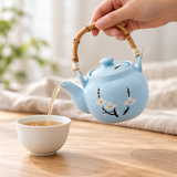Pale blue blossom teapot pouring tea into a separate cup