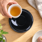 Black teacup trivet viewed overhead as a small teacup is placed toward its center