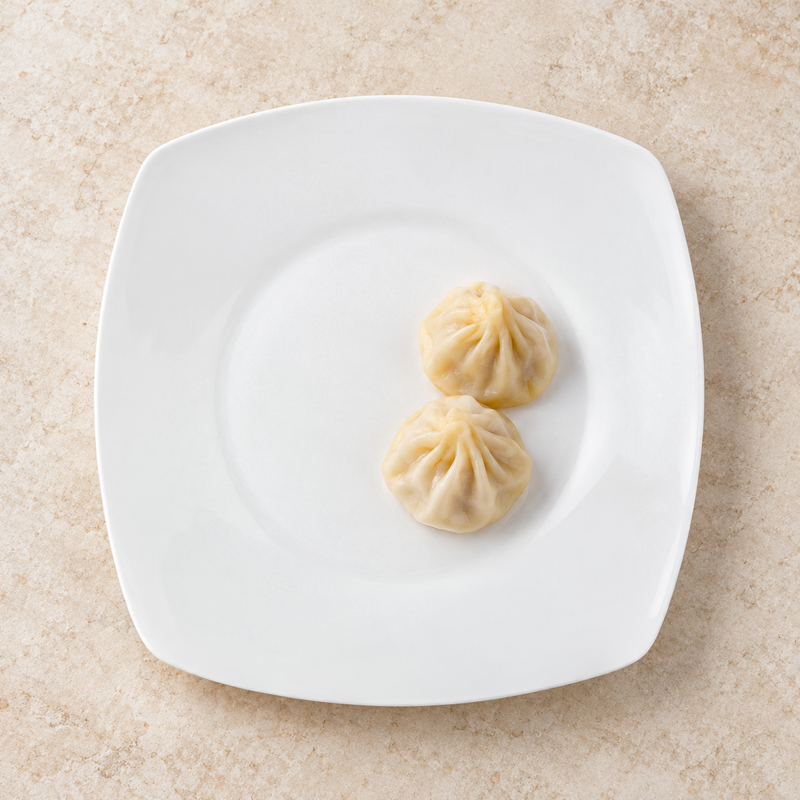 White rounded-square ceramic plate with steamed dumplings