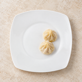 White rounded-square ceramic plate with steamed dumplings