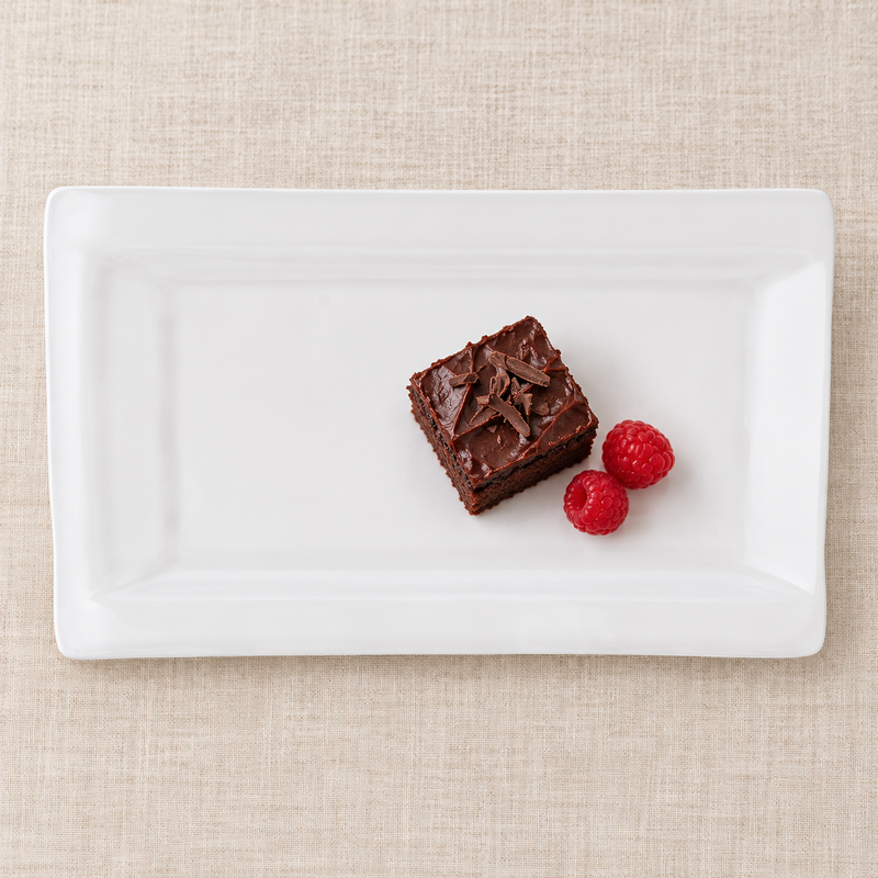 White rectangular ceramic platter with chocolate cake and raspberries