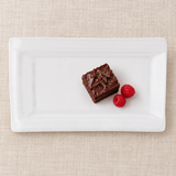 White rectangular ceramic platter with chocolate cake and raspberries