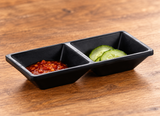 Matte black two-compartment sauce dish with chili sauce and cucumber pickles