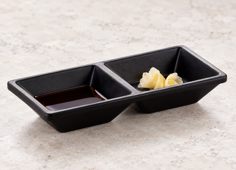 Matte black two-compartment sauce dish with soy sauce and pickled ginger
