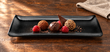 Textured matte-black rectangular platter with chocolate truffles and raspberries
