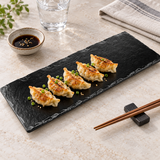 YG-1015MB black slate-style melamine platter with five gyoza beside soy sauce, chopsticks and a water glass