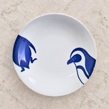 Blue penguin-design ceramic plate on a stone tabletop