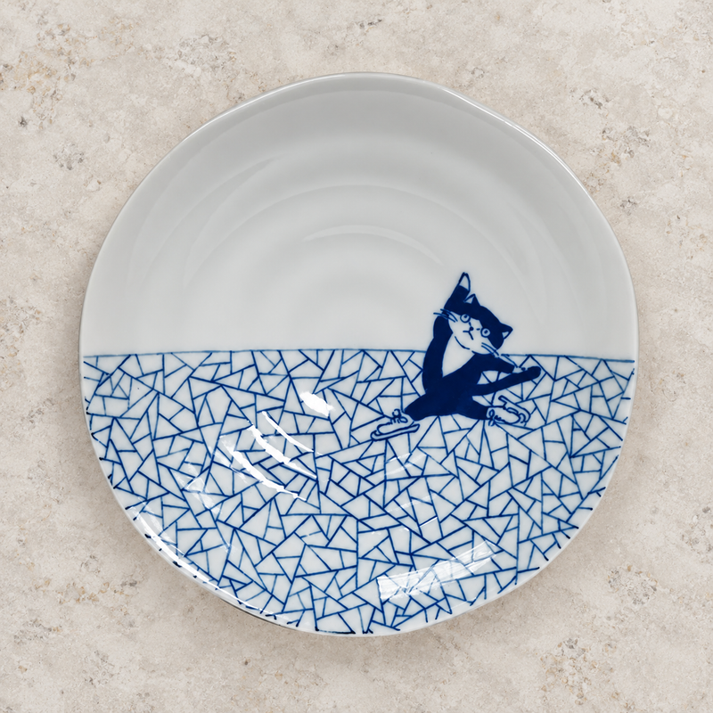 6½″ Blue & White Ceramic Skating Cat Round Plate — pattern viewed from above on a light stone surface