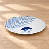 Blue umbrella-cat ceramic plate on a wood tabletop