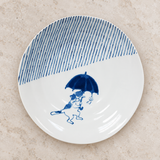 Blue umbrella-cat ceramic plate on a stone tabletop