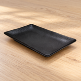 Black rectangular ceramic plate on a wood tabletop