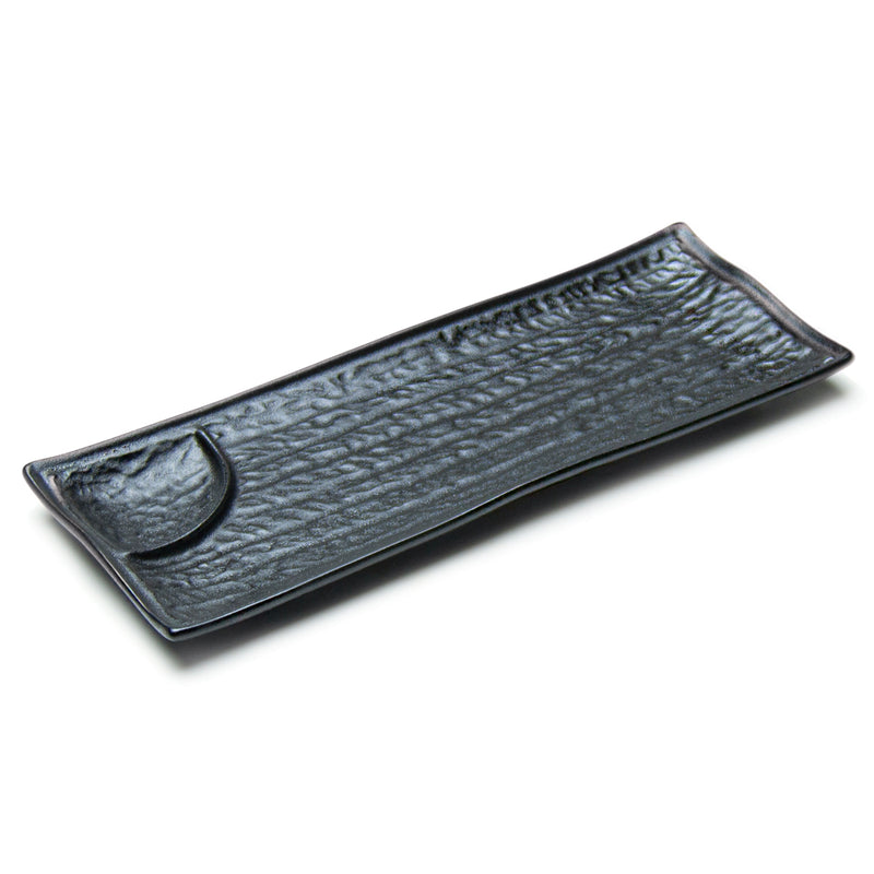 Black rectangular porcelain plate with a small curved sauce well at one end and textured-looking main surface.